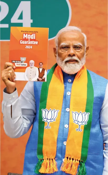  ?? — REUTERS ?? Indian Prime Minister Narendra Modi displays a copy of the Bharatiya Janata Party’s manifesto for the general election in New Delhi on Sunday.