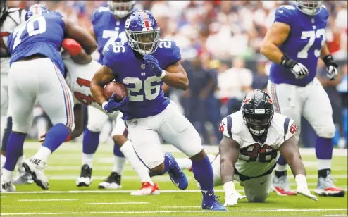  ?? Tim Warner / Getty Images ?? Giants running back Saquon Barkley (26) breaks free during Sunday’s win over the Texans in Houston.
