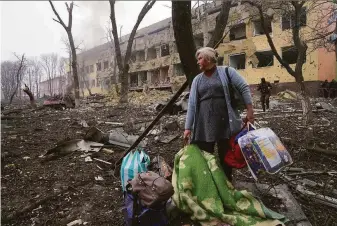  ?? Evgeniy Maloletka / Associated Press ?? A woman walks outside a maternity hospital that was damaged by shelling in Mariupol, Ukraine. Russia continues to pound a steel plant that is the last bastion of resistance in the city.