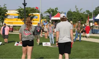  ?? (Caitlan Butler/ News-Times) ?? Delek workers and their families compete in a cornhole tournament during a centennial celebratio­n of the El Dorado refinery on Saturday at the MAD Amp.