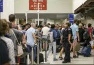  ?? THE ASSOCIATED PRESS ?? A police officer stands guard as passengers wait in line at Terminal 7 in Los Angeles Internatio­nal Airport on Sunday.