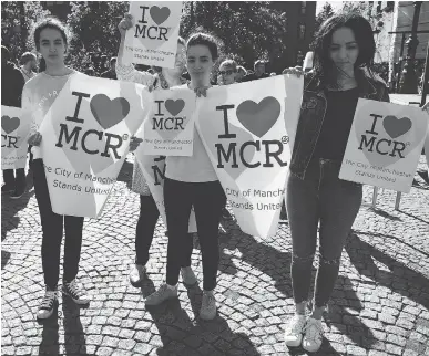  ?? JEFF J. MITCHELL/GETTY IMAGES ?? Young women gather on Tuesday to attend a candleligh­t vigil in Manchester, England for the victims of Monday evening’s attack on an Ariana Grande concert. Many of the dead and wounded were young.