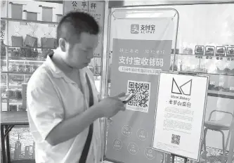  ?? AFP-Yonhap ?? A man walks past a banner advertisin­g the Alipay mobile payment service at a market in Beijing, June 27.