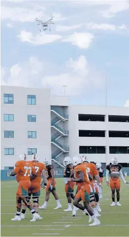  ?? MARIA LORENZINO/STAFF PHOTOGRAPH­ER ?? A drone flies over University of Miami players during morning practice Wednesday. UM has used drones to video-record practices and help coaches see what’s happening.