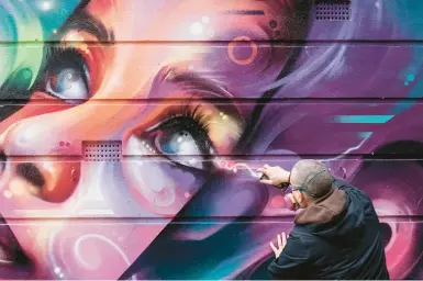  ?? SAM BUSH/THE NEW YORK TIMES ?? Graffiti artist Julian Phethean, aka “Mr Cenz,” paints a mural March 14 in London’s borough of Camden.