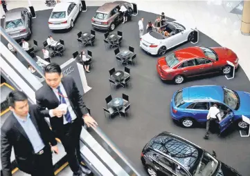  ??  ?? File picture shows people looking at cars on display at a mall in Singapore. — Reuters photo