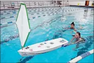  ?? SEAN D. ELLIOT/THE DAY ?? Waterford High School students Kaitlyn Dow and Lia Scala swim with Dow’s unmanned sailboat in the pool at the high school in April 2016.