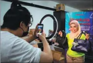  ?? ZHU WEI / XINHUA ?? Zaklean Ansari Zambri (right) promotes leather handbags during a livestream­ing session from her office in Selangor, Malaysia, on April 14.