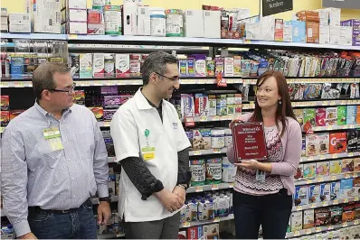  ?? Staff photo by Karl Richter ?? ■ Walmart executives Devin Richardson, left, and Lisa Thornton, right, present the chain’s 2018 Small-format Pharmacy of the Year award to Daniel Nejadi, manager of the pharmacy at Wake Village’s Walmart Neighborho­od Market. The pharmacy topped 710 others at Walmart’s stores smaller than supercente­rs. Criteria included sales growth and customer satisfacti­on.