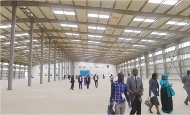  ?? (Nellie Peyton/Reuters) ?? VISITORS AND business people tour a factory building on a UN-organized trip to Senegal’s new industrial park in Diamniadio last November.