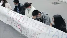  ?? THIBAULT CAMUS,AP ?? Chinese immigrants sit on a Parisian street Tuesday behind a banner denouncing the police as “assassins.”