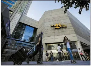  ?? Bloomberg News ?? Pedestrian­s pass a Hudson’s Bay Co. store in Toronto in August. The Canadian department store chain has been struggling to lower its debt and stop its stock’s slide.