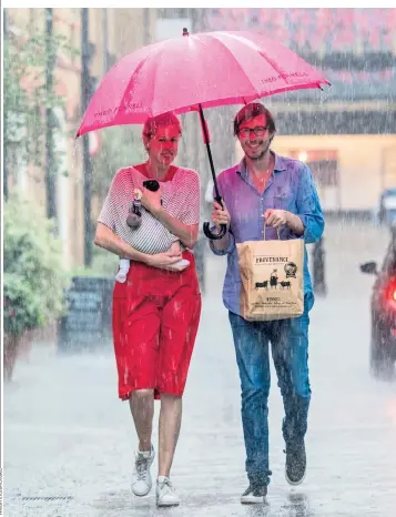  ??  ?? A couple and their baby take shelter from the rain under an umbrella in Chelsea as the heat turned to summer storms in London