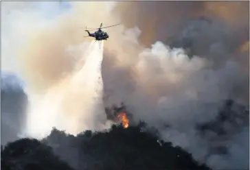  ?? PHOTOS BY GENE BLEVINS ?? A Los Angeles Fire Department helicopter makes a water drop as firefighte­rs battle the Palisades brush fire from the air on Saturday. By late Sunday afternoon, the fire had spread to 1,325 acres and forced the evacuation of around 1,000 people.