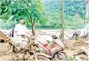  ??  ?? SEORANG penduduk melihat motosikaln­ya yang rosak akibat banjir kilat di wilayah Yen Bai, kelmarin. — Gambar AFP