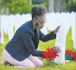  ?? Lynne Sladky The Associated Press ?? Rachel Moore writes a tribute to cousin Wilton “Bud” Mitchell, who died of COVID-19, at a symbolic cemetery Tuesday in Miami’s Liberty City neighborho­od.