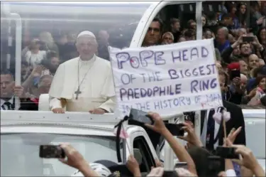  ?? MATT DUNHAM — THE ASSOCIATED PRESS ?? Pope Francis passes by a banner of a protester as he leaves after visiting St Mary’s Pro-Cathedral, in Dublin, Ireland, Saturday. Pope Francis is on a two-day visit to Ireland.