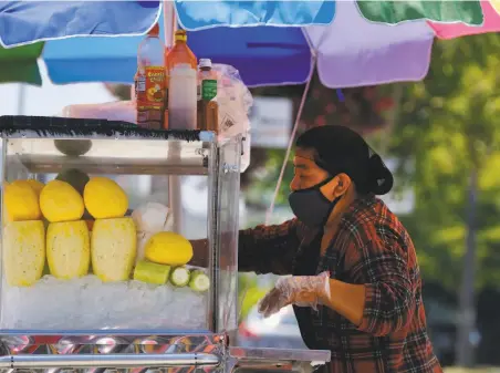  ?? Richard Vogel / Associated Press ?? A fruit vendor works in Los Angeles. A bill would require employers to notify workers about exposure to the coronaviru­s.