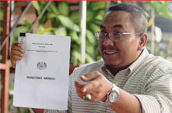  ?? PIC BY SHARUL HAFIZ ZAM ?? Kedah Pas deputy commission­er Muhamad Sanusi Md Nor, who is also chairman of a special committee for Memali victims, holding the White Paper on the 1986 Memali incident, in Sik yesterday.