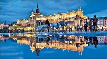  ?? DOMINIC ARIZONA BONUCCELLI/RICK STEVES’ EUROPE ?? A rain puddle reflects the floodlit charm of Cloth Hall, one of several major buildings on Krakow’s Main Market Square.