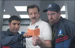  ??  ?? Head coach Ted Lasso (Jason Sudeikis, center) and his assistant coach (Brendan Hunt, right) take a look at a play drawn up by team kit man Nathan (Nick Mohammed) in an episode of “Ted Lasso.”