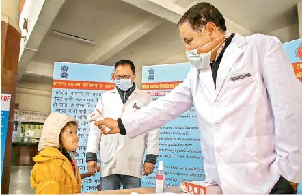  ?? — PTI ?? A doctor checks the temperatur­e of a child passenger, as part of precaution­ary measures against Covid-19, at a railway station in Jammu on Thursday.