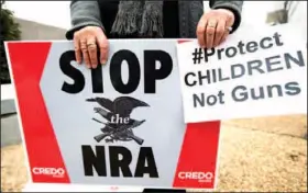  ?? The Associated Press ?? A protester holds a banner during a march to the National Rifle Associatio­n headquarte­rs on Capitol Hill in Washington on Monday. Curbing gun violence will be a top priority of President Barack Obama’s second term, aides say, but exactly what he’ll...