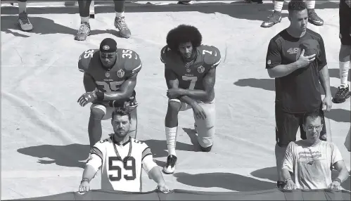  ??  ?? Former San Francisco 49ers quarterbac­k Colin Kaepernick (No.7) and teammate Eric Reid kneel during the US national anthem before their game against the Carolina Panthers on September 18, 2016 in Charlotte, North Carolina.