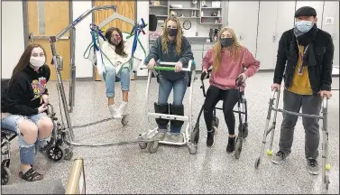  ?? (Courtesy Photo/Lonnie Moll) ?? Ambry Smith (left), Ithzel Martinez, Josie Newsom, Cora Bass and Dylan Her, students in the CNA and PCA classes at Gentry High School, spend some time in mobility devices to learn what it’s like to depend on such devices for mobility.