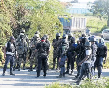  ?? KENYON HEMANS/PHOTOGRAPH­ER ?? Policemen and soldiers gather to search a heavily vegetated section along the Spanish Town Bypass where four robbers who targeted a credit union in Portmore escaped after abandoning a Nissan Latio motor car.