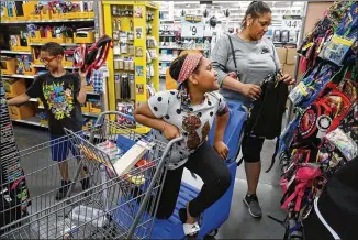  ?? NUCCIO DINUZZO / CHICAGO TRIBUNE ?? Lavinia Johnson, with her children Micah Blanks, 11, and Brooklyn Banks, 10, shop for back-to-school supplies in late July at a Wal-Mart in Chicago. Research shows children enjoy the brick-and-mortar experience where they can see and touch the items...