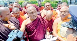  ?? PIC BY WARUNA WANNIARACH­CHI ?? Monks speaks with the policemen outside Police Head Quarters before going to hand over the petition asking for the arrest of Minister Rishad Bathiudeen and Governor Eastern Province M. L. A. M. Hizbullah.