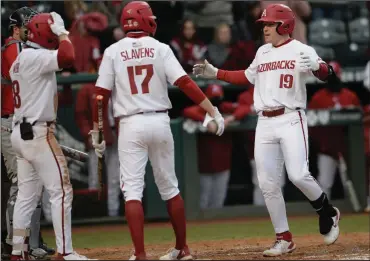  ?? (NWA Democrat-Gazette/Andy Shupe) ?? Arkansas designated hitter Charlie Welch (right) is congratula­ted by teammates Brady Slavens (17) and Braydon Webb after hitting a home run during Friday’s victory over Southeast Missouri State at Baum-Walker Stadium in Fayettevil­le. The Razorbacks hit four home runs in the game. More photos available at arkansason­line.com/227semoua.