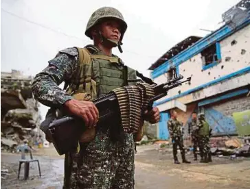  ??  ?? ASKAR kerajaan berkawal di bangunan dan rumah yang musnah akibat pertempura­n di Marawi. - Agensi