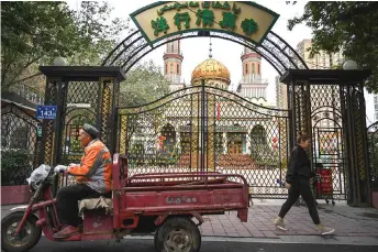  ??  ?? People walking past a mosque in Urumqi, the regional capital of Xinjiang.