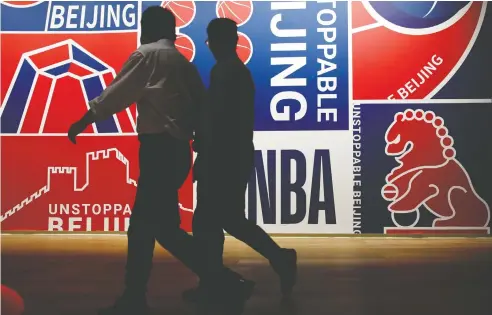  ?? JASON LEE / REUTERS ?? Men walk past an NBA poster in Beijing on Tuesday. Below: Houston Rockets GM Daryl Morey has angered China with a pro-Hong Kong tweet.