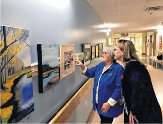  ?? ERIC BOURQUE ?? Simone Sweeney, left, of the Yarmouth Hospital Auxiliary, and Lynn Burke-Newell, administra­tive assistant, nursing administra­tion, at the Yarmouth Regional Hospital, get a closer look at one of the pieces in a new art project at the Yarmouth hospital, where an art gallery has been set up in the first-floor corridor connecting buildings B and C.