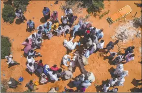  ?? (AP) ?? Medical workers in protective suits bury the body of an elderly man believed to have died from the coronaviru­s in Mogadishu, Somalia.