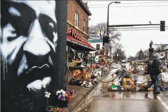  ?? Chandan Khanna / AFP via Getty Images ?? A man passes a makeshift memorial for George Floyd on March 10 in Minneapoli­s. A federal grand jury indictment accuses expolice of violating the Black man’s constituti­onal rights.