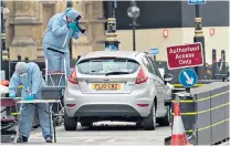  ??  ?? Protected: forensic officers examine the car that drove into cyclists and barriers outside the Palace of Westminste­r this week