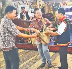  ??  ?? Martin (second left) receives the ‘buwis’ (gift) from Albert (right). The ‘buwis’ used to be presented to Gawai guests during the old days.