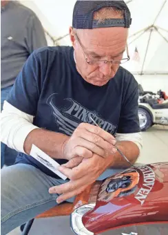  ??  ?? Pinstripe artist Jim Brando of Gurnee, Ill., paints a portrait of Beethoven, the bike owners' dog, on a bike. See more photos at jsonline.com/news.