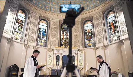  ?? EMILY LESHNER/AP ?? The Rev. Steven Paulikas, right, and curate Spencer Cantrell deliver an Evening Prayer service over Facebook Live in March in New York City.