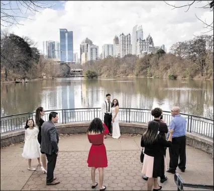  ?? STEVE SCHAEFER / CONTRIBUTE­D ?? Among the scenes across Atlanta on the day that President-elect Donald Trump disparaged much of the city as “falling apart”: Alexander and Jocelyn Garcia are surrounded by family while having their wedding photograph­s taken in Piedmont Park on Saturday.