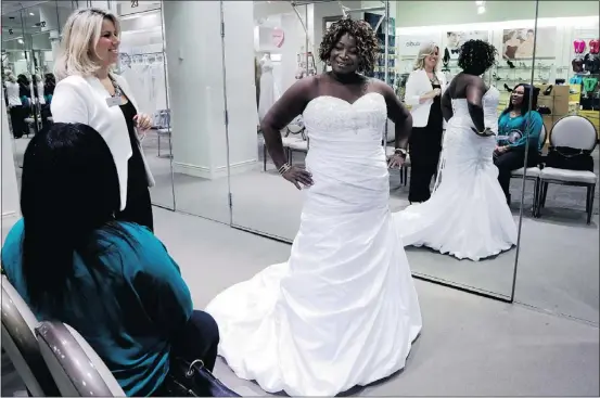  ?? — THE ASSOCIATED PRESS FILES ?? Yolanda Royal, 64, right, tries on wedding dresses for an $11,000 reception for about 100 people.