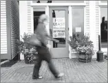  ?? ROBERT F. BUKATY/AP ?? A shopper walks past one of several vacant retail spaces among outlet shops last month in Freeport, Maine.