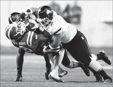  ?? Photograph­s by Wally Skalij Los Angeles Times ?? BELLFLOWER St. John Bosco’s Stephan Blaylock, front, and Clive Manuao tackle Santa Ana Mater Dei receiver Amon-Ra St. Brown in the first quarter of the rout at Santa Ana Stadium.