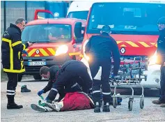  ??  ?? A wounded migrant is treated after shots were fired near Calais on Thursday, left, and migrants yesterday queueing for food