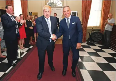  ??  ?? Boris Johnson is welcomed to Number 10 Downing Street by cabinet secretary Sir Mark Sedwill. Dominic Cummings lurks in the right-hand corner