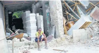  ?? AP ?? A man sits in front of a collapsed funeral home in Les Cayes, Haiti, on Monday, two days after a 7.2-magnitude earthquake struck the southweste­rn part of the country.